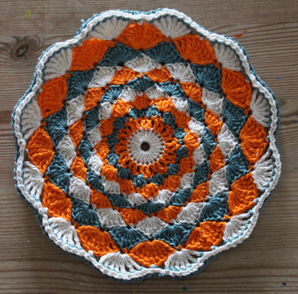 hæklet cirkel i muslingemønster - 22,5 cm i diameter - grøn-orange med grøn kant